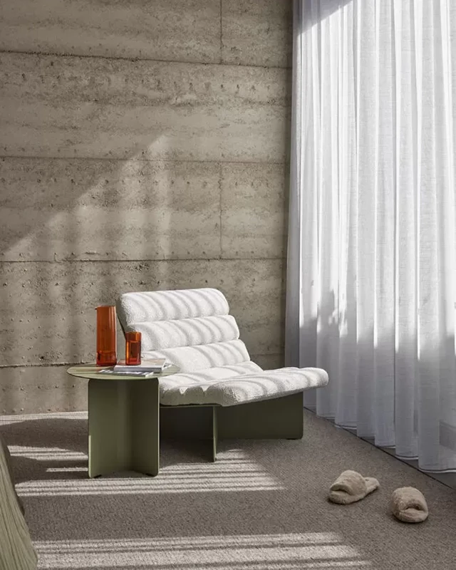 A room with an empty Tait Voom lounge chair facing at the curtains.