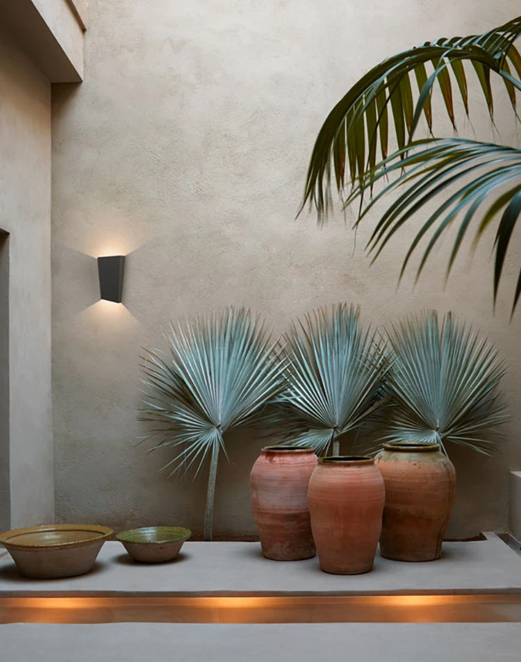 A courtyard with plants and Vibia wall lighting.