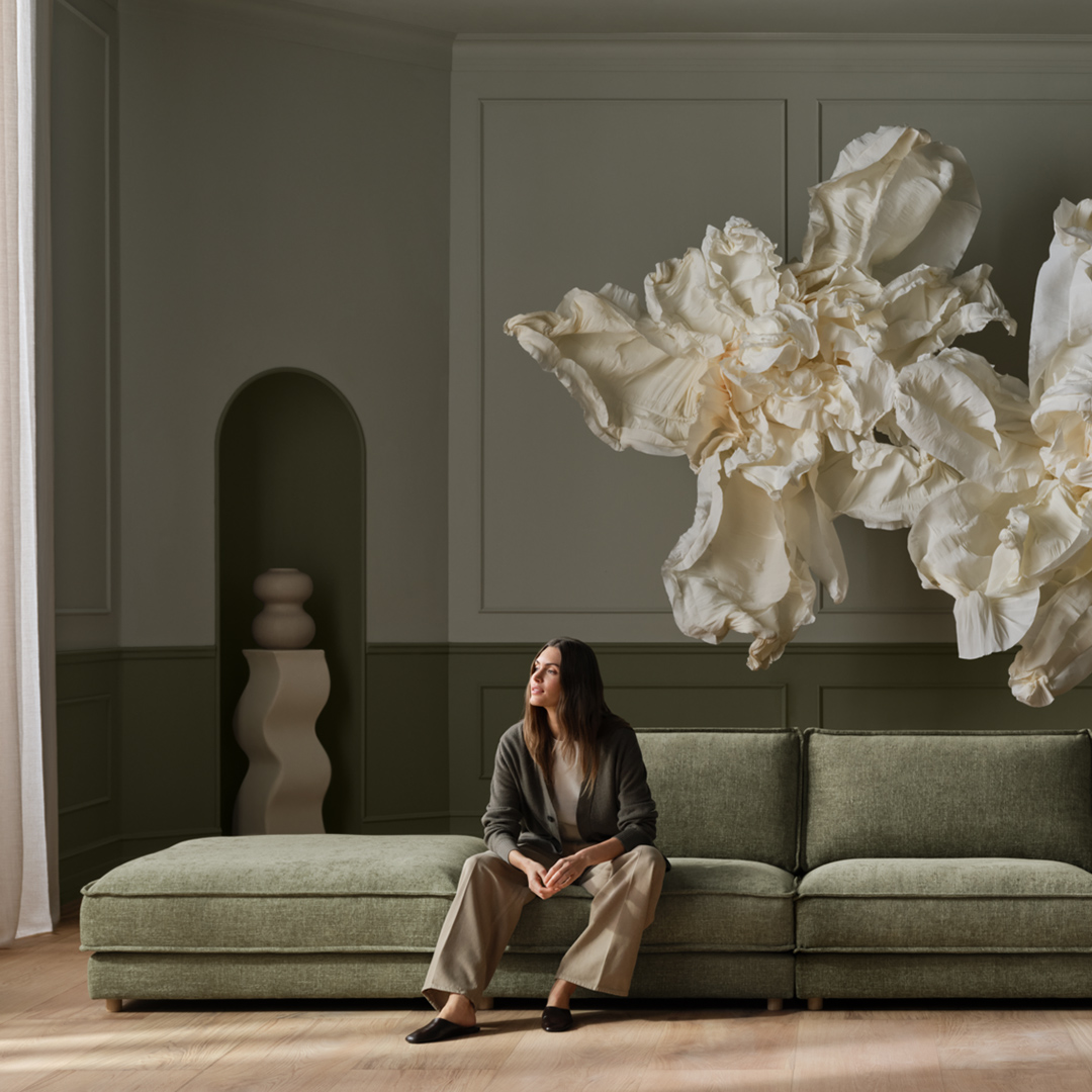 The Viccarbe Savina Sofa in green in a architectural setting with a pendant hanging over and a floor to ceiling window overlooking a vine garden